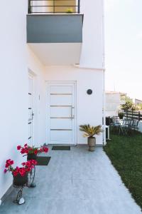 a white house with a white door and red flowers at Sithon Diamond Suites 2 in Nikiti