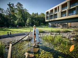 a woman standing in the water in front of a building at Deltapark Vitalresort Seevillen in Thun