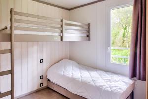 ein kleines Schlafzimmer mit Etagenbetten und einem Fenster in der Unterkunft Escapade entre ocean et foret a Pont-l Abbe in Pont-lʼAbbé
