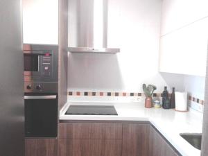 a kitchen with a microwave and a stove top oven at Apartamento El Diario in Adra
