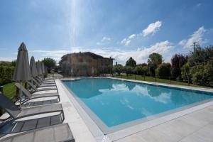 uma grande piscina com espreguiçadeiras e guarda-sóis em Azienda Agrituristica Armea em Desenzano del Garda