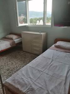a bedroom with two beds and a dresser and two windows at Dena apartman Tivat in Tivat