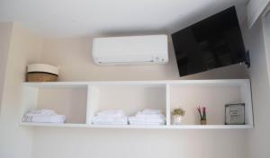 a room with white shelves with a television and towels at Astorga suites in Astorga