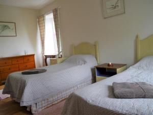 a bedroom with two beds and a dresser and a window at The Drovers Cabin in Kirkcudbright