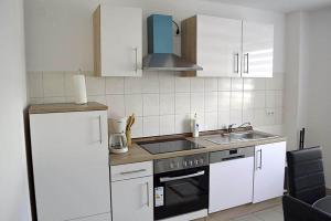 a kitchen with white cabinets and a sink and a refrigerator at Zwei Raben Pension in Mainz