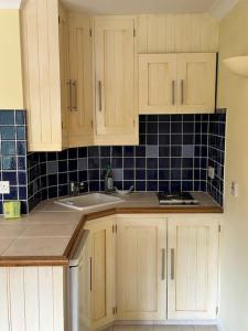 a kitchen with white cabinets and a sink at Maywoods Apartment in Virginia Water