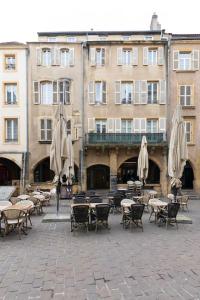 a courtyard with tables and umbrellas in front of a building at Bohemian Bakoua & Chesterfield Cottage, hyper-centre in Metz