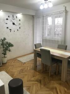 a dining room with a table and a clock on the wall at Apartman Bazar in Smederevo