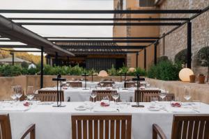 un restaurante con mesas blancas y sillas con copas de vino en Son Brull Hotel & Spa, en Pollensa