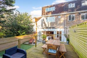 eine Terrasse mit einem Holztisch und einem Holzzaun in der Unterkunft Family home close to Bournemouth town centre in Bournemouth