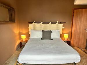 1 dormitorio con 1 cama blanca grande y 2 lámparas en Locanda Il Cortile, en Vignale