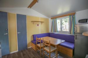une salle à manger avec une table et un canapé bleu dans l'établissement mobil-home du lac de Foix, à Foix