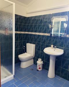 W wyłożonej niebieskimi kafelkami łazience znajduje się toaleta i umywalka. w obiekcie Gold Guest House & Bar w mieście Përmet