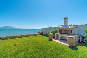 a backyard with a grill in the grass with the ocean at Villa Angelos in Nerátza