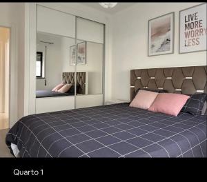 een slaapkamer met een groot bed en een spiegel bij Apartamento Feliz in Figueira da Foz