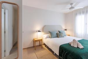 a white bedroom with a bed and a mirror at NEW Stylish 2 Bedroom Apt in Las Palmas de Gran Canaria