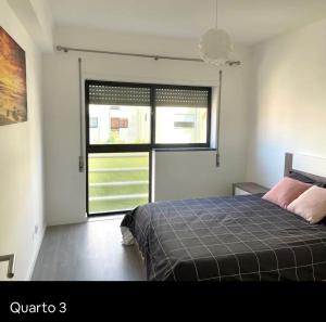 een slaapkamer met een bed en een groot raam bij Apartamento Feliz in Figueira da Foz