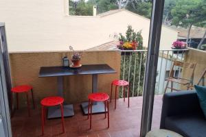 a balcony with a table and four red stools at Résidence le Formentor in Leucate