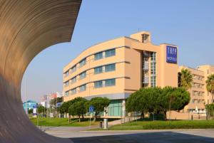 a large tan building with a large arch in front of it at TRYP by Wyndham Porto Expo Hotel in Leça da Palmeira