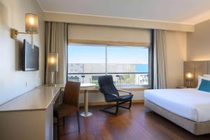 a hotel room with a bed desk and a bed and a window at TRYP by Wyndham Porto Expo Hotel in Leça da Palmeira