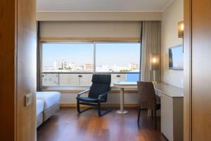 a hotel room with a desk and a bed and a window at TRYP by Wyndham Porto Expo Hotel in Leça da Palmeira