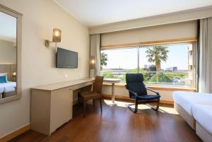 a hotel room with a desk and a bed and a window at TRYP by Wyndham Porto Expo Hotel in Leça da Palmeira