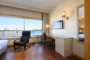a hotel room with a desk and a bed and a window at TRYP by Wyndham Porto Expo Hotel in Leça da Palmeira
