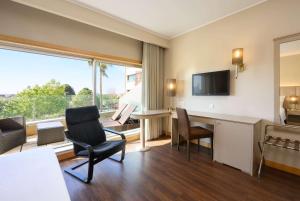 a hotel room with a desk and chairs and a large window at TRYP by Wyndham Porto Expo Hotel in Leça da Palmeira