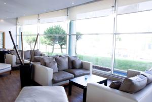 a living room with couches and tables and large windows at TRYP by Wyndham Porto Expo Hotel in Leça da Palmeira