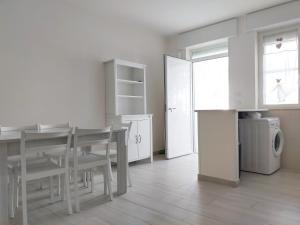 biała kuchnia ze stołem i pralką w obiekcie A due passi sul mare w mieście San Pietro in Bevagna