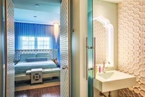 a bedroom with a bed and a sink and a mirror at Dream South Beach, Part Of Hyatt in Miami Beach