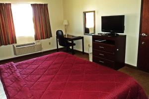een hotelkamer met een bed, een bureau en een televisie bij Travelodge by Wyndham Carlsbad NM in Carlsbad