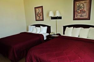 2 bedden in een hotelkamer met rode lakens bij Travelodge by Wyndham Carlsbad NM in Carlsbad
