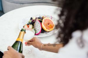 a woman holding a bottle of champagne next to a plate of fruit at Dream Hollywood in Los Angeles