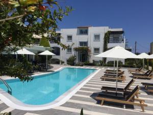 a swimming pool with chairs and umbrellas next to a building at Sandy's Cycladic Style Apartment in Gouves