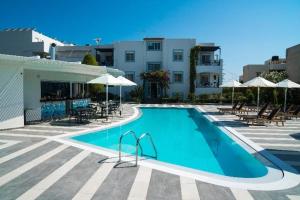 una piscina con sillas y sombrillas y un edificio en Sandy's Cycladic Style Apartment, en Gouves