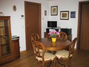 uma mesa de madeira com cadeiras e um vaso de flores em Appartamento Vacanze da Jolanda em Tarvisio