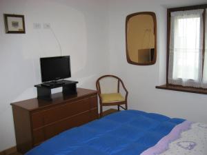 um quarto com uma cama e uma cómoda com uma televisão em Appartamento Vacanze da Jolanda em Tarvisio