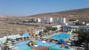 a resort with a pool with chairs and umbrellas at Tiwaline Tarsime App F in Sidi Ifni