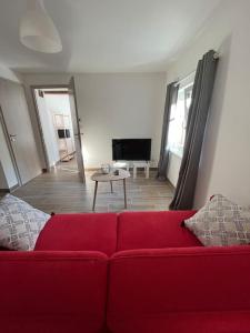 a living room with a red couch and a table at Doux Refuge avec Terrasse PARKING GRATUIT in Beblenheim