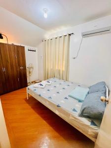 um quarto com uma cama e piso em madeira em Awesome 2 bedrooms, living & dining area em General Trias
