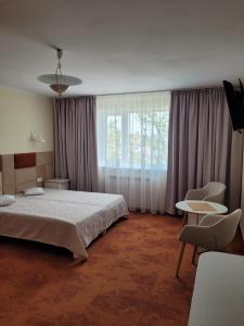 a bedroom with a bed and a window and chairs at Damroka in Łeba