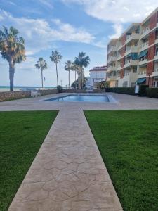 una piscina con palme e un edificio di Apartament Les Delícies a Sant Carles de la Ràpita