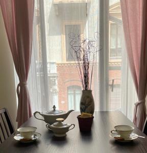 Una mesa con dos juegos de té y una ventana. en La Casa di Ringhiera - silenzioso appartamento di charme con balcone nel quadrilatero romano, en Turín