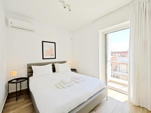 a white bedroom with a large white bed and a window at Nemeseos Apartments by Verde in Athens