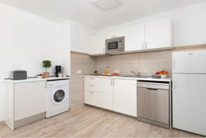 een keuken met witte kasten en een wasmachine en droger bij Aptos dOr in Cala d´Or