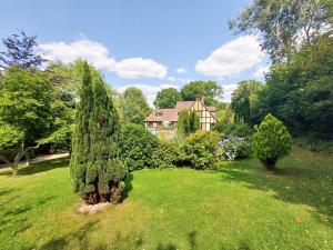 un jardín con árboles y una casa al fondo en Kipling Cottage, en Burwash