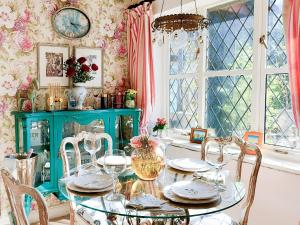a dining room with a table with chairs and a clock at Kipling Cottage in Burwash