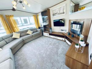 uma sala de estar com um sofá e uma televisão de ecrã plano em Superb Caravan At Steeple Bay Holiday Park In Essex, Sleeps 6 Ref 36081d em Southminster