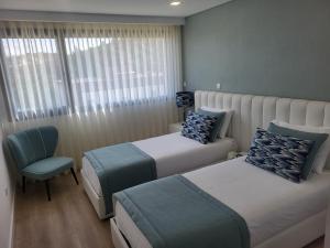 ein Hotelzimmer mit 2 Betten und einem Stuhl in der Unterkunft NORTHEAST PORTUGAL G in Mirandela